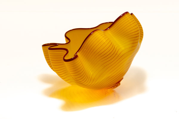 Two abstract blown-glass sculptures by Dale Chihuly in vivid saffron yellow, featuring organic, seaform-inspired shapes with contrasting lip wraps; one larger and one smaller form are displayed together, emphasizing scale, color saturation, and biomorphic movement characteristic of Chihuly's modern glass work.
