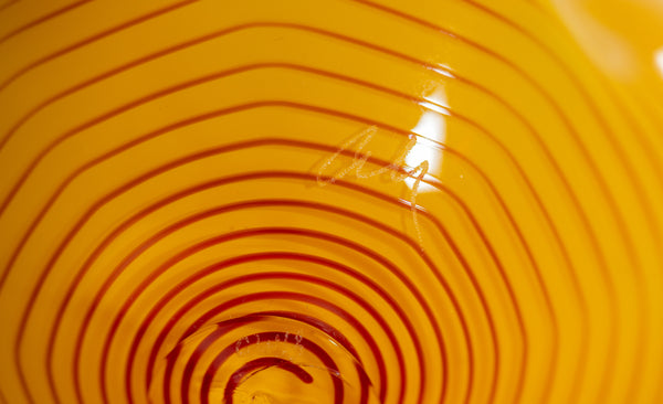 Two abstract blown-glass sculptures by Dale Chihuly in vivid saffron yellow, featuring organic, seaform-inspired shapes with contrasting lip wraps; one larger and one smaller form are displayed together, emphasizing scale, color saturation, and biomorphic movement characteristic of Chihuly's modern glass work.