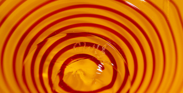 Two abstract blown-glass sculptures by Dale Chihuly in vivid saffron yellow, featuring organic, seaform-inspired shapes with contrasting lip wraps; one larger and one smaller form are displayed together, emphasizing scale, color saturation, and biomorphic movement characteristic of Chihuly's modern glass work.