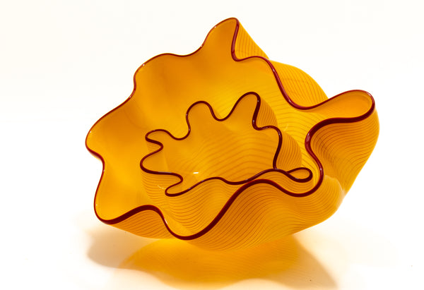 Two abstract blown-glass sculptures by Dale Chihuly in vivid saffron yellow, featuring organic, seaform-inspired shapes with contrasting lip wraps; one larger and one smaller form are displayed together, emphasizing scale, color saturation, and biomorphic movement characteristic of Chihuly's modern glass work.