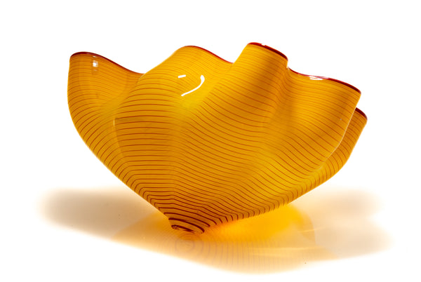Two abstract blown-glass sculptures by Dale Chihuly in vivid saffron yellow, featuring organic, seaform-inspired shapes with contrasting lip wraps; one larger and one smaller form are displayed together, emphasizing scale, color saturation, and biomorphic movement characteristic of Chihuly's modern glass work.