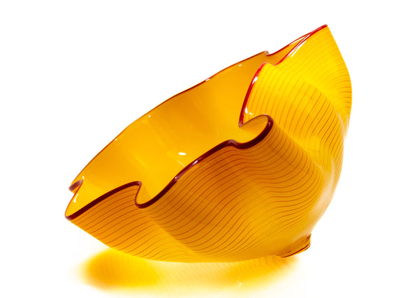 Two abstract blown-glass sculptures by Dale Chihuly in vivid saffron yellow, featuring organic, seaform-inspired shapes with contrasting lip wraps; one larger and one smaller form are displayed together, emphasizing scale, color saturation, and biomorphic movement characteristic of Chihuly's modern glass work.