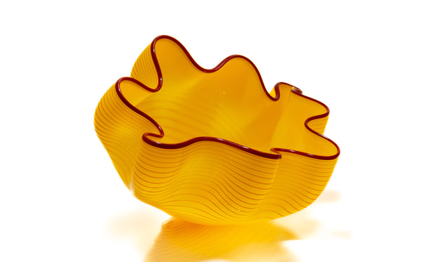 Two abstract blown-glass sculptures by Dale Chihuly in vivid saffron yellow, featuring organic, seaform-inspired shapes with contrasting lip wraps; one larger and one smaller form are displayed together, emphasizing scale, color saturation, and biomorphic movement characteristic of Chihuly's modern glass work.