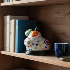 "Nana" by Niki de Saint Phalle is a charming limited-edition porcelain sculpture from her iconic Nanas series. Standing 5 inches high, this white partially glazed figure features vibrant polychrome decoration, bold curvaceous forms, and expressive vitality celebrating femininity and empowerment.